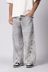 Pantalón de jean con corte baggy y fit oversize, de color gris con efecto lavado ácido. Presenta costuras reforzadas y diseño de pierna ancha.