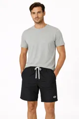 Short de corte recto confeccionado en poliéster, color negro, con cintura elástica ajustable mediante cordón blanco y bolsillos laterales.