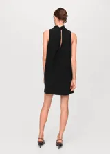 Vestido corto negro sin mangas, con cuello alto tipo halter y panel frontal semitransparente. Presenta un diseño recto y minimalista.