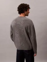 Sweater de punto Calvin Klein gris melange, con cuello redondo, manga larga y logo institucional "ck" en relieve en el centro del pecho. Corte regular.
