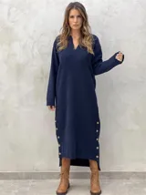 Vestido midi de punto color azul marino, con cuello en V, mangas largas y diseño holgado. Presenta un patrón de rombos en relieve y aberturas laterales con botones decorativos en el ruedo.