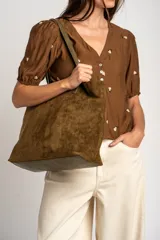 Blusa de viscosa color marrón, con escote en V, mangas cortas abullonadas y cierre frontal con botones. Cuenta con pequeños detalles bordados distribuidos por la prenda.
