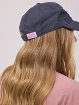 Gorro de visera color lila, estilo dad hat, de lona lavada con bordado frontal en blanco que dice "RUSTY AUSTRALIA MERMAID BEACH".