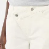 Pantalón de twill color beige, de corte ancho, con cintura asimétrica y cierre de botón descentrado.