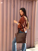 Cartera shopper de cuero color marrón chocolate, con doble asa de hombro, bolsillo frontal externo y diseño estructurado.
