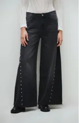 Pantalón de jean negro con efecto lavado, corte wide leg y aberturas laterales con detalle de tachas plateadas.