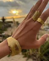 Brazalete rígido plateado con textura irregular.