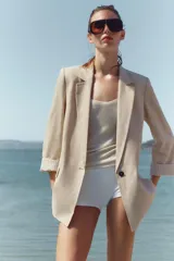 Blazer de lino color verde militar, con cuello solapa, hombreras y manga larga con puño revuelto con detalle a rayas. Cuenta con cierre frontal de un botón y bolsillos delanteros con solapa.