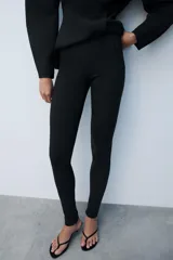 Leggings negros de tiro alto con bolsillos falsos de vivo en el delantero y cierre lateral con cremallera oculta. Presentan cremalleras ocultas en los bajos.