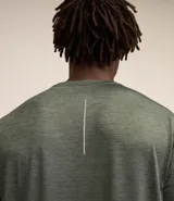 Remera deportiva masculina de manga corta con cuello redondo, confeccionada en tejido técnico con tecnología Dry para mayor transpirabilidad. Presenta detalles reflectantes en los hombros y un diseño liso en color verde melange.