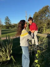 Sweater artesanal tejido en mohair, de corte holgado y manga larga. Presenta un diseño de cuello redondo con un patrón geométrico en forma de picos en color amarillo sobre una base gris.