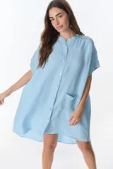 Vestido camisero corto color celeste, de lino, con cuello mao, botones frontales, mangas cortas con detalle de tejido calado y un bolsillo de parche tejido en el frente.