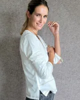 Remera blanca de manga larga con cuello en V y costuras decorativas en contraste. Incluye un lazo ajustable en el cuello con herraje metálico circular.