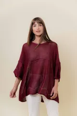 Buzo de tejido liviano color vino tinto con brillo sutil tipo lurex, cuello redondo y calce suelto (oversize) con mangas amplias. Presenta terminación especial en ruedo y puños.
