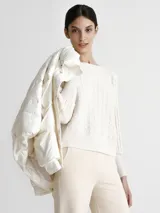 Campera puffer color blanco nacarado, con cuello alto y cierre frontal con botones a presión.