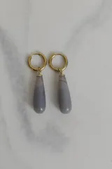 Aros tipo argolla con dije colgante en forma de gota de piedra natural gris. Fabricados en acero quirúrgico dorado.