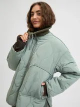 Campera acolchada de color gris oscuro, con diseño matelaseado de ondas, cuello alto en rib, cierre frontal con cremallera metálica y bolsillos frontales aplicados.
