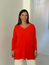 Sweater de punto color naranja, con cuello en V, manga larga y diseño holgado con bolsillos frontales y tajos laterales.