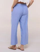 Pantalón crop de lino y rayón, con diseño wide leg de corte holgado, estampado tropical de hojas en tonos verde, azul y marrón sobre fondo blanco. Cuenta con pretina trasera elastizada y bolsillos delanteros.