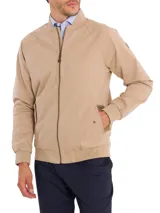 Campera bomber color beige de sarga de algodón orgánico con calce regular. Tiene cierre frontal, dos bolsillos delanteros con tapeta y snaps ocultos, dos bolsillos internos, puños, cuello y pretina de rib. El interior está forrado con franela.