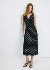 Vestido midi negro con estampado de lunares blancos, escote en pico con detalle de encaje, tirantes y diseño fluido de corte recto.