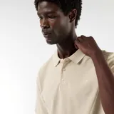 Remera polo de piqué color beige, de manga corta, con cuello camisero y cierre frontal de tres botones.