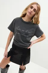 Remera negra de algodón con efecto lavado, manga corta y cuello redondo. Presenta una estampa frontal con la frase escrita en letras brillantes de estilo cursivo.