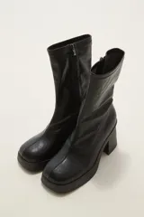 Bota de caña media en cuero sintético color negro, con plataforma y taco cuadrado. Presenta costura central en el empeine y cierre lateral interno.