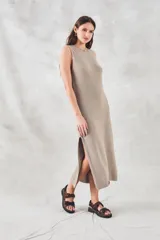Vestido midi sin mangas, confeccionado en tejido de punto de algodón con textura tipo waffle. Presenta un corte recto, cuello redondo y aberturas laterales pronunciadas en el ruedo.