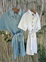 Vestido camisero corto de jean celeste con botones dorados y lazo en la cintura.
