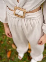 Mono largo color avena, con escote en V, mangas 3/4 abullonadas y detalle de abertura en la cintura con hebilla cuadrada de rafia.