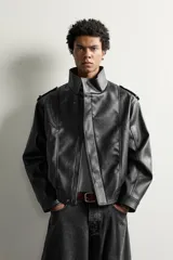 Cazadora biker relaxed fit confeccionada en tejido efecto piel, color negro. Cuenta con cuello subido, manga larga con puño ajustable y bajo elástico. Incluye bolsillos de vivo en la cadera y cierre frontal con cremallera oculta bajo una solapa diagonal con botones a presión.