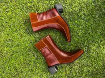 Bota corta de cuero color bordó, con punta cuadrada y taco bloque bajo. Cierre lateral con cremallera.