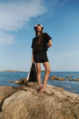 Short negro de tiro alto confeccionado en lino y rayón, con cierre invisible y doble botón lateral.