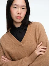 Sweater de tejido con textura peluda, color marrón, con cuello tipo polo y mangas largas. Presenta un diseño de silueta cómoda y holgada.