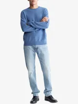 Sweater de punto color azul melange, con cuello redondo, manga larga y acabados acanalados en puños y bajo. Presenta un pequeño logo bordado en el pecho.