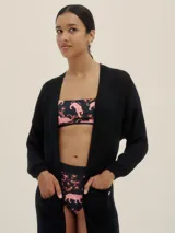 Cárdigan largo tejido en jersey color negro, con bolsillos delanteros y detalle de logo en cobre.