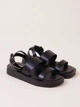 Sandalias negras con plataforma, tiras anchas y hebilla al tobillo.