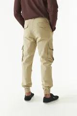 Pantalón cargo gris con puños elásticos, corte regular, bolsillos laterales con solapa y pasacintos.