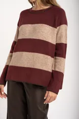 Sweater de punto con diseño de rayas horizontales anchas en color bordó y beige. Presenta cuello redondo con detalle de lurex, mangas largas y puños y ruedo acanalados.