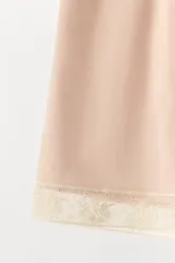 Shorts de tiro alto confeccionados en tejido satinado color beige, con cintura elástica y detalle de aplicación de encaje en el bajo.