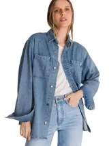 Camisa oversize de denim azul de la marca Cat, de manga larga con puños abotonados, cuello camisero y cierre frontal de botones. Presenta doble bolsillo en el pecho con etiqueta de la marca y dobladillo tipo cola de camisa.