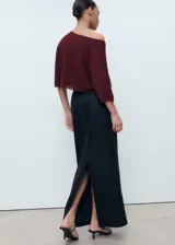 Jersey de punto fino con diseño oversize, cuello barco y mangas acampanadas. Presenta un corte cropped y costura central vertical en el frente.