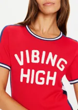 Remera de tejido punto color rojo, manga corta, corte ajustado (slim fit) con cuello redondo ribeteado en blanco y azul marino. Presenta franjas laterales en azul marino con ribete blanco y texto estampado en blanco en el frente que dice "VIBIN HIGH".