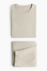 Pijama de dos piezas confeccionado en punto cepillado de viscosa. Incluye una remera de manga larga con cuello redondo y detalles de terminación ondulada en puños y bajo, y un pantalón de corte recto con cintura elástica y terminación ondulada en el ruedo.