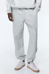 Pantalón de jogging gris claro, de corte relajado, con cintura elástica ajustable con cordón, bolsillos laterales y puños acanalados.