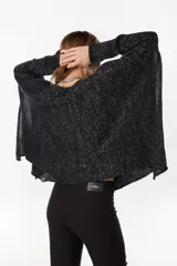 Poncho oversize de tejido de punto con hilos de lurex, color negro, con escote redondo y aberturas laterales en las mangas.