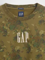 Buzo de cuello redondo, manga larga y calce holgado, color verde militar con estampado floral camuflado. Presenta el logo "GAP" bordado en el pecho en color blanco.