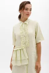 Vestido camisero color verde claro con rayas verticales, cuello clásico, cierre frontal con botones y mangas cortas. Presenta volados frontales y laterales.