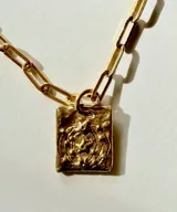 Collar de plata con medalla rectangular texturizada e incrustaciones de cristales verdes, suspendido de una cadena de eslabones.